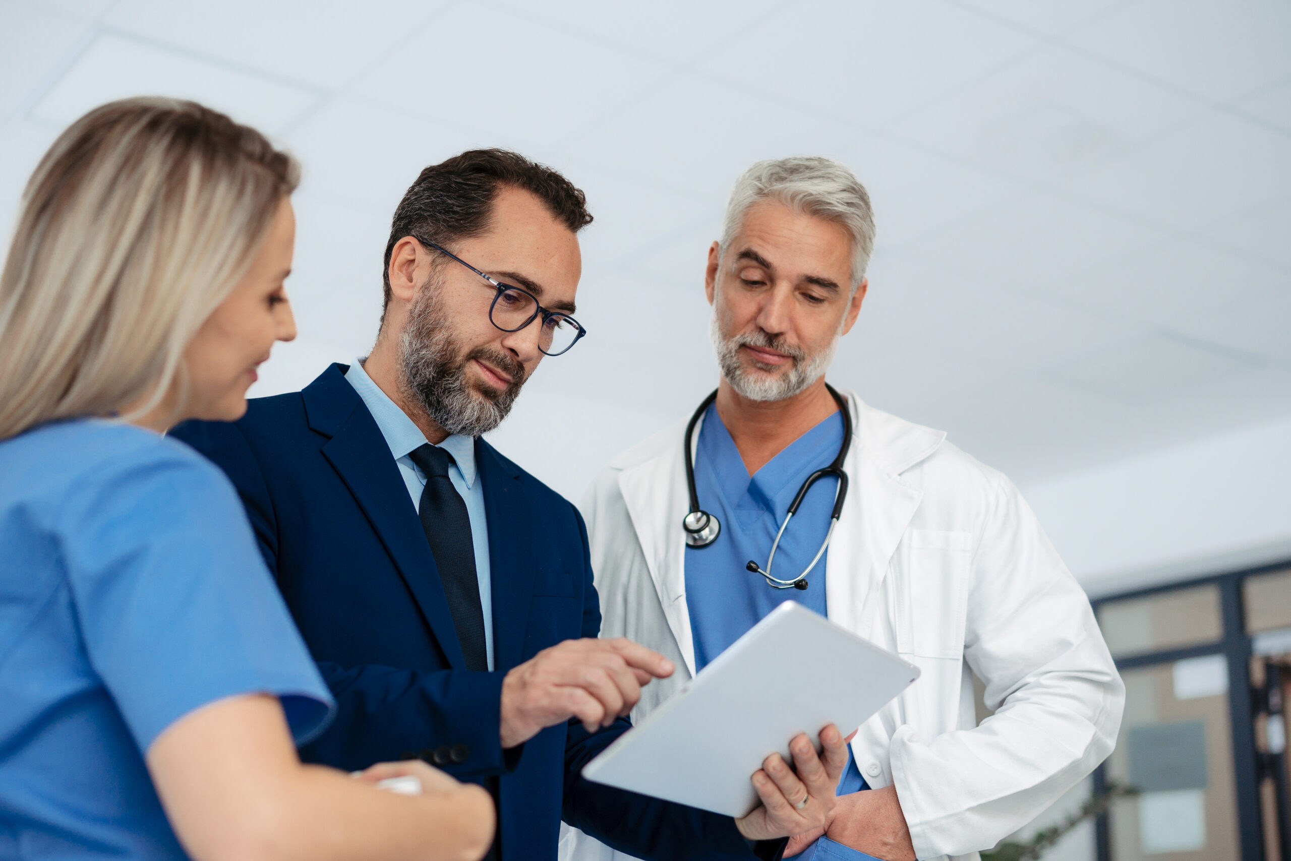 A practice administrator showing something on a tablet to a nurse and a physician in a clinic